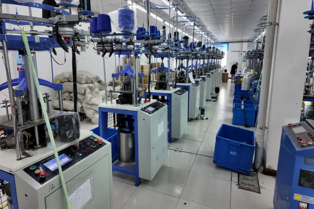 Rows of circular knitting machines operating in a sports brace factory for knitted support component production.